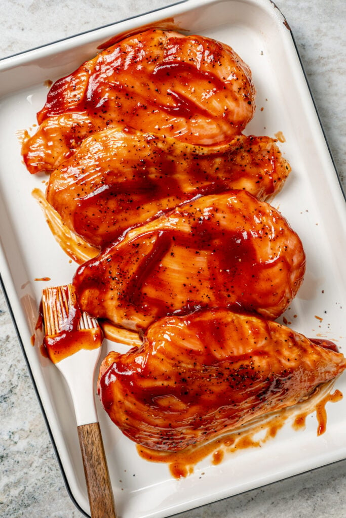 Brushing the cooked chicken with BBQ sauce. 