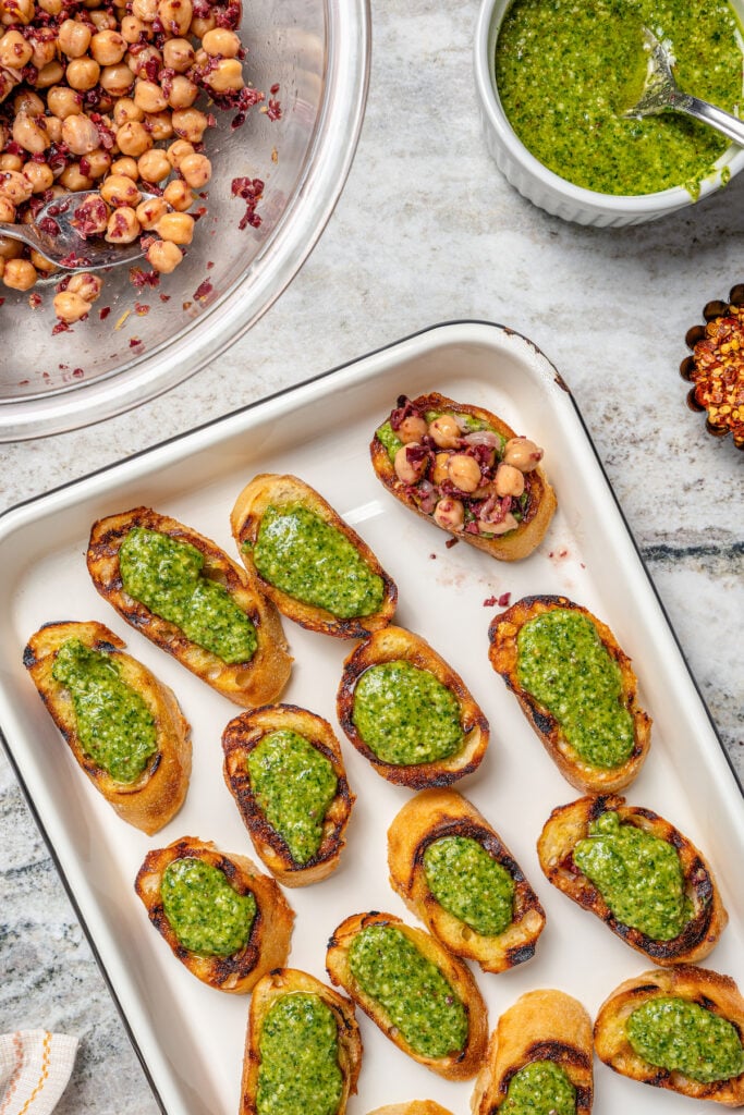 Assembling the appetizers with pesto and the chickpea mixture.