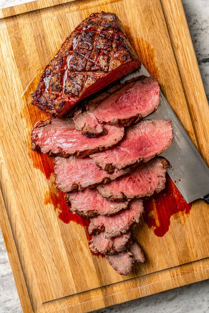 Thinly slicing the beef roast after grilling. 