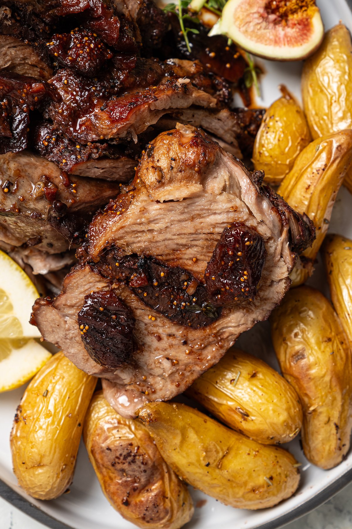 Sliced pork shoulder recipe with fig sauce and mini potatoes on the side.