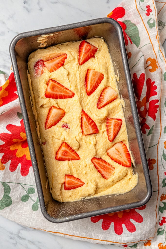 Spreading the batter in the greased loaf pan. 